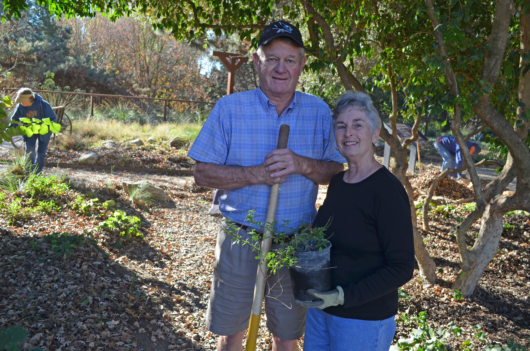 Fred and Martha Rehrman posing, one holding a plant, the other a shovel