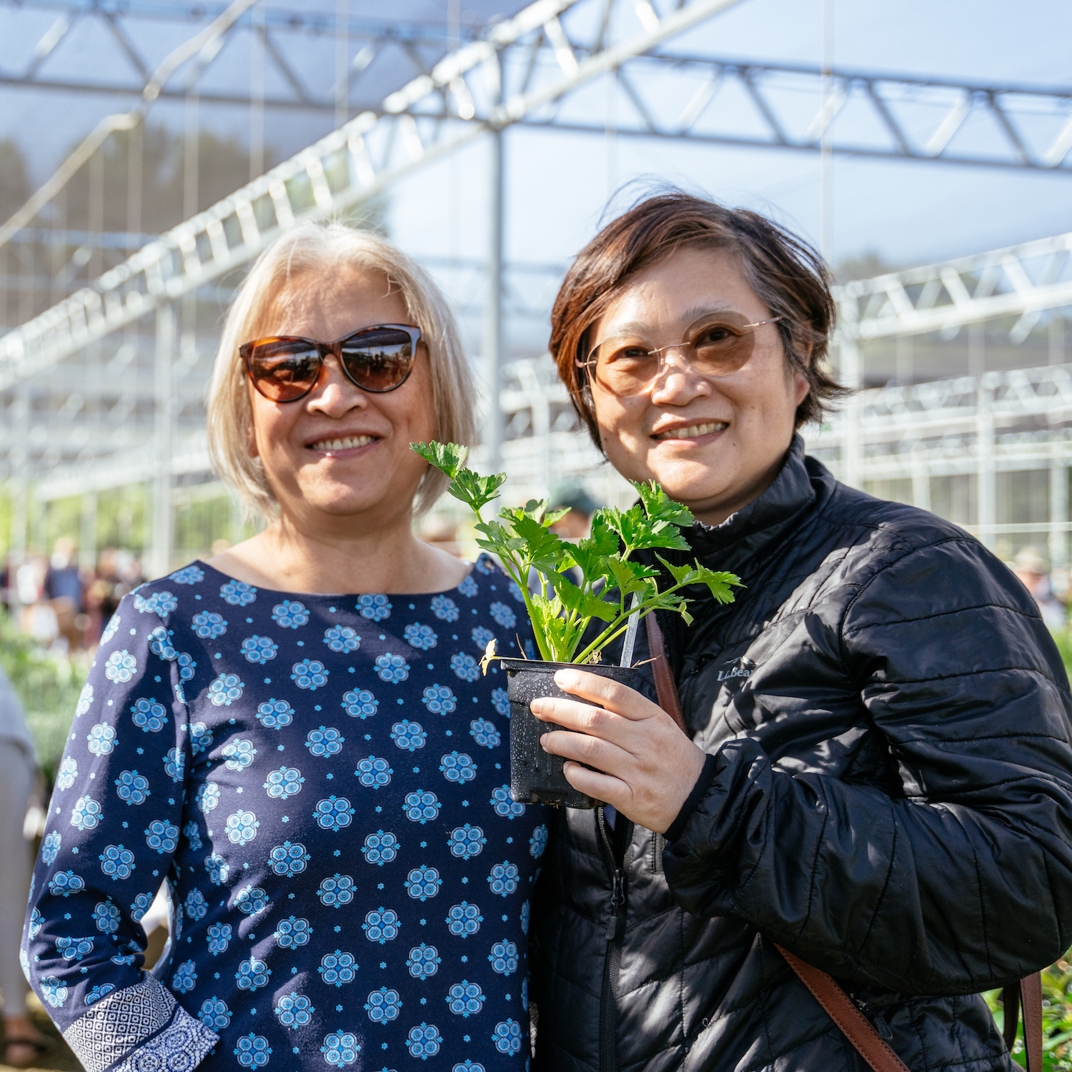 Two visitors pose with a plant in the Arboretum Teaching Nursery