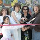 Group of people cutting ribbon in front of the mosaic mural of the Nature's Gallery Court.